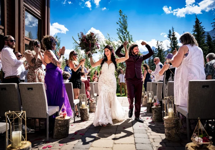 Happy Newlyweds walk down the aisle while guests cheers them after wedding ceremony .