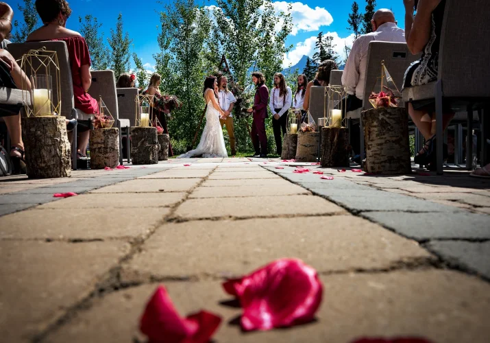 Wedding ceremony in Banff with red rose petals on the ground.