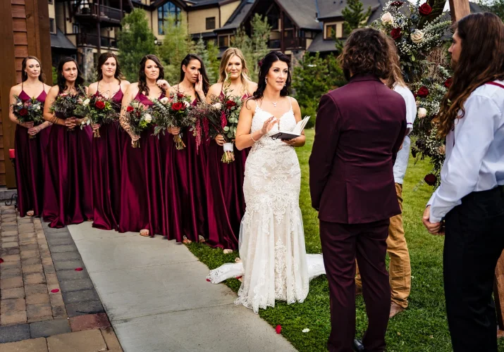 Bride gives a speech on the Wedding Ceremony in Banff. Bridesmaids in red dresses stand next to the bride.