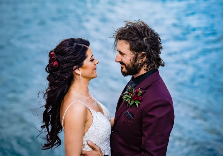 Newlyweds look into each others eyes at Minnewanka Lake in Banff.
