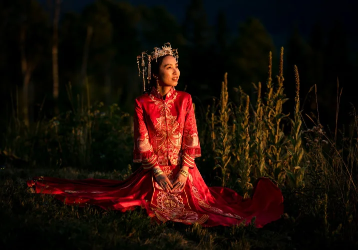 Amazing portrait of the bride sitting in the sun . She wears red, traditional Asian wedding dress.