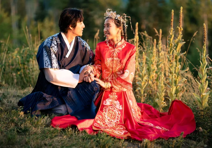 Bride and groom st at the grass. They wear beautiful Asian traditional outfit.
