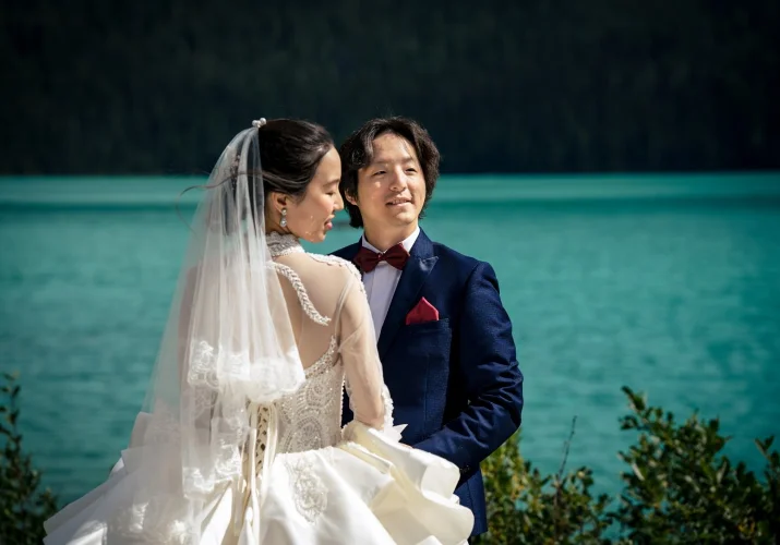 Colourful portrait of bride and groom standing in the sun by the Emerald Lake.