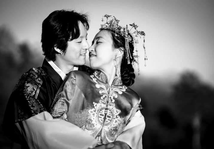 Newlyweds share a kiss. The groom standing behind his wife.