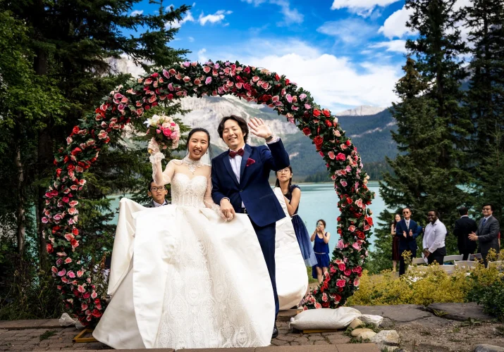 Happy newlyweds after amazing wedding ceremony at Emerald Lake. They smile and the bride lifts her flowers.