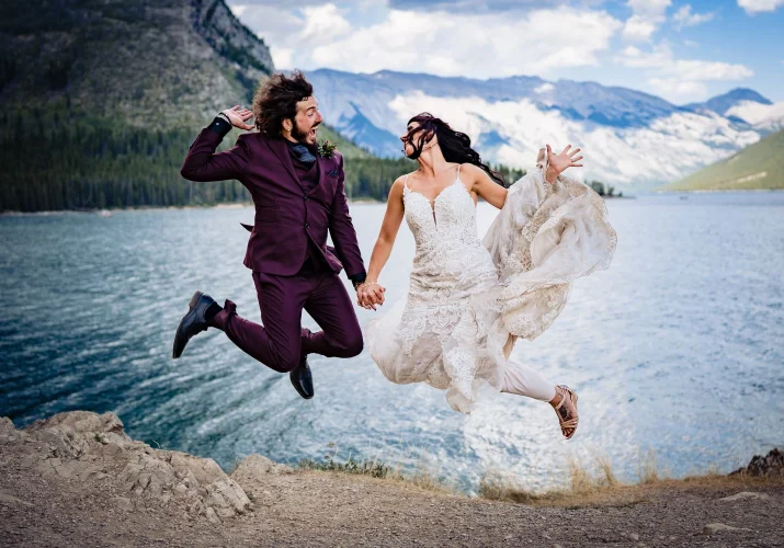 Funny jump of bride an groom by the lake.