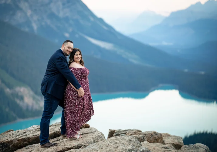 man hugs is fiancee from behind at turquoise Peyto Lake in Banff National Park.