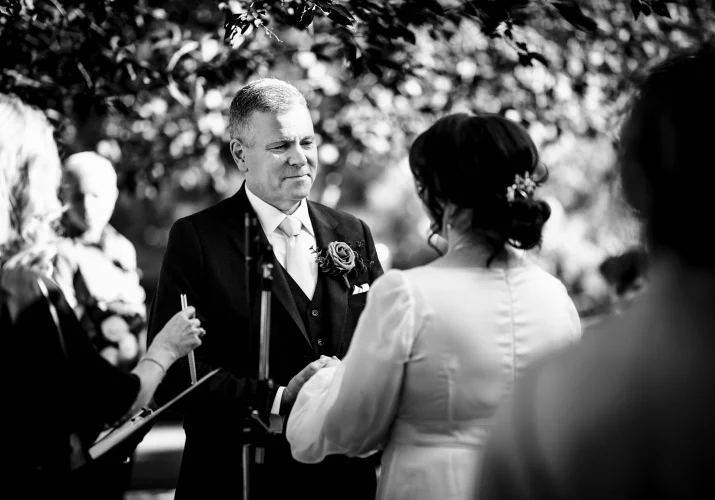 Groom holds the bride's hand during their wedding ceremony in Calgary ZOO