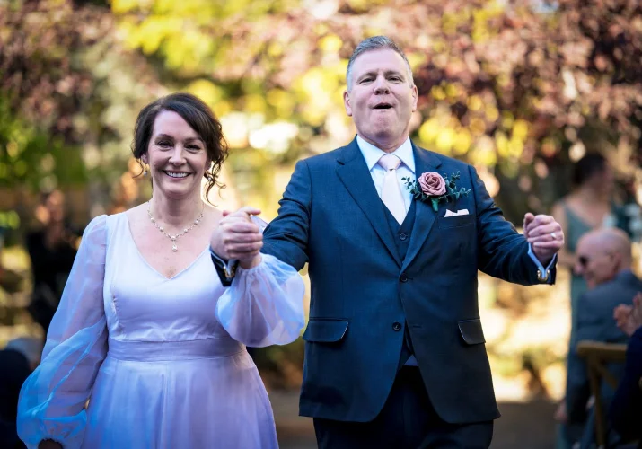 Happy Newlyweds leaving wedding ceremony in Calgary ZOO, holding their hands and smiling.