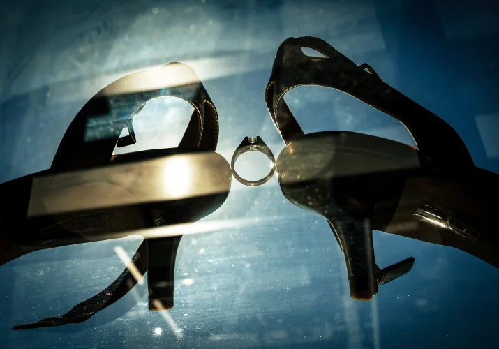 Wedding ring between bride's wedding shoes.