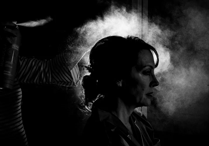 Photograph in black and white of bride getting her hair sprayed .