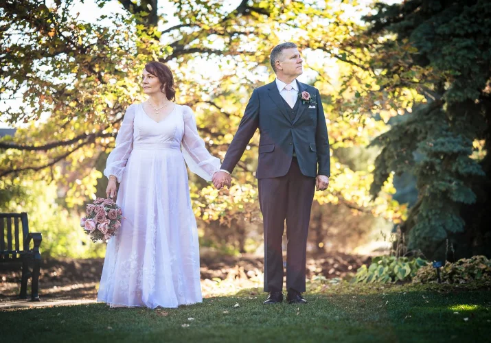 Bride and groom holds their hands while looking in different directions. Calgary Zoo Wedding.