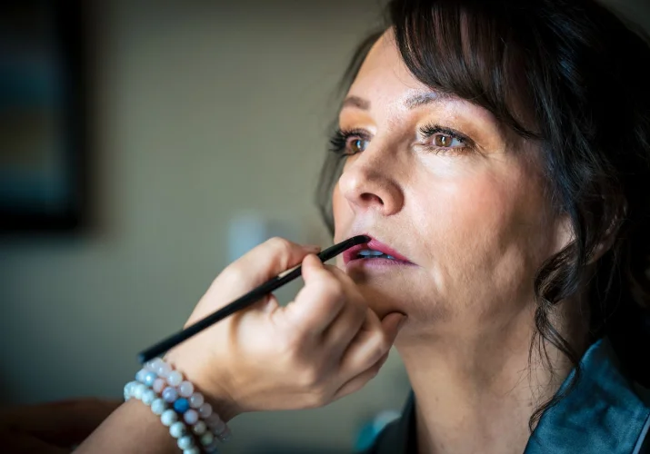 Make up artist puts on the bride's lips a lipstick.