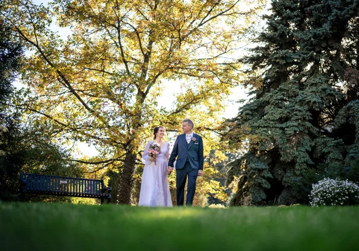 Handsome newlyweds walking holding their hands in Calgary Zoo during the fall.