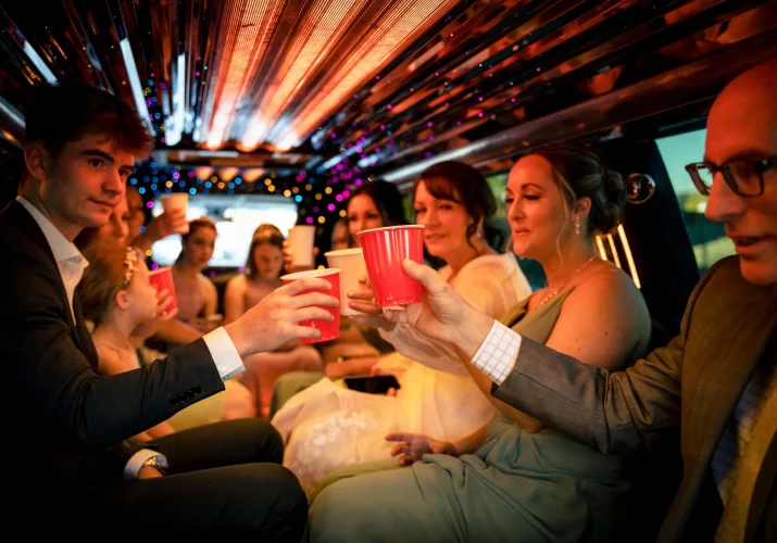 Bridal-party drinks champagne form the red cups in the limo.