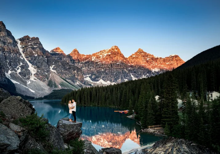 Banff Wedding Photography of engaged couple at Moraine Lake. They hug each other against massive Canadian Rockies.