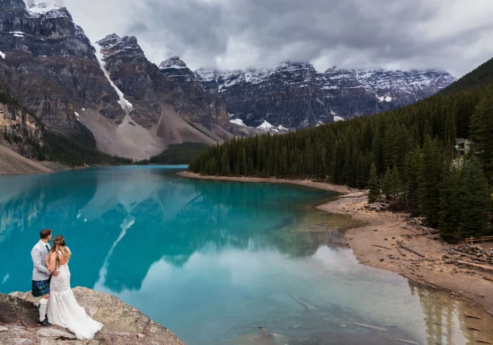 Bride and groom look and the fascinating , turquoise Glacier lake - Moraine Lake.