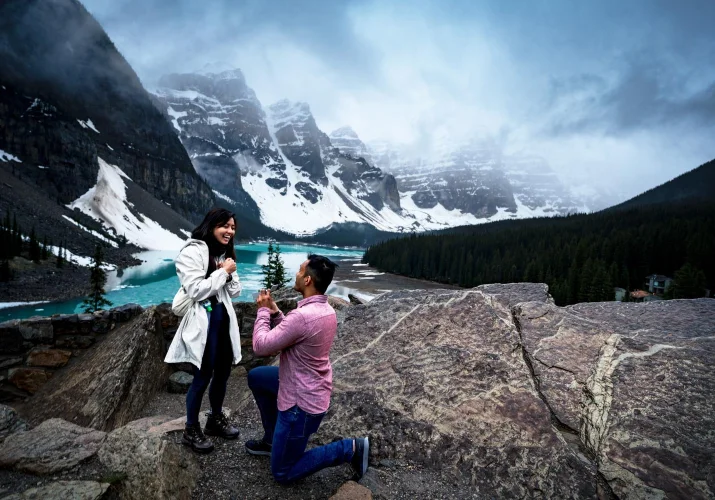 Man goers down the knee with the engagement ring and propose at Moraine Lake. Moment captured by the best Calgary Wedding Photographers.