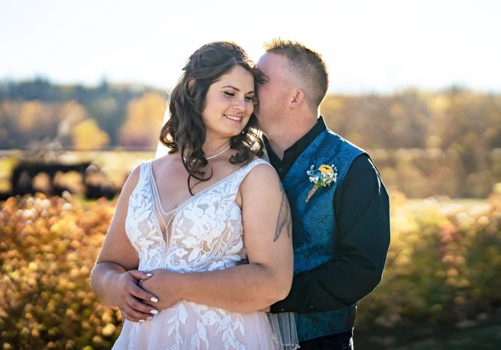 Groom whispers a secret into the bride's ear. Fall after-wedding session taken by Calgary Wedding Photographer
