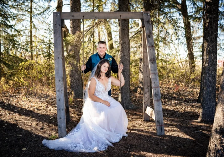 Fall Calgary Wedding Photography of the bride sitting at the swing and the groom standing behind her.