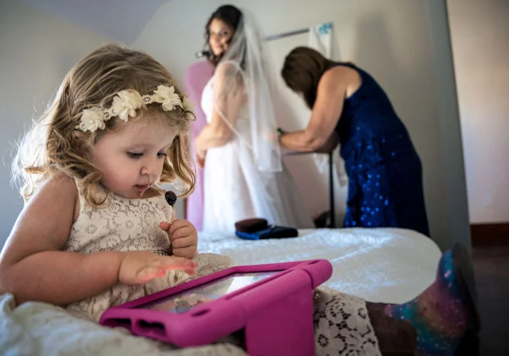 Flower-girl plays games on IPad while the bride is getting ready to attend Calgary Wedding Ceremony.