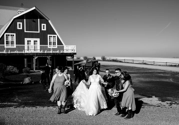Wedding Party walking in front of the venue building in Calgary They talk with each other and have fun. Photograph in black and white taken by Banff Wedding Photographer. .