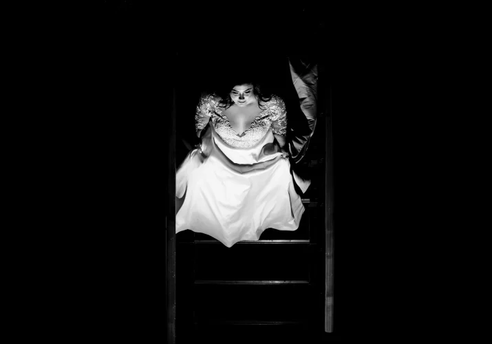 Black and white photograph of the bride walking down the stairs.