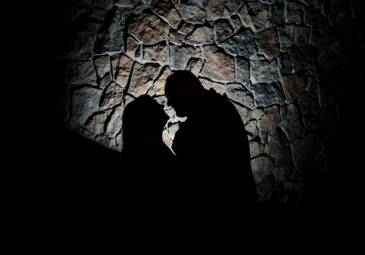 silhouetted photo of the bride and groom against stoned wall.