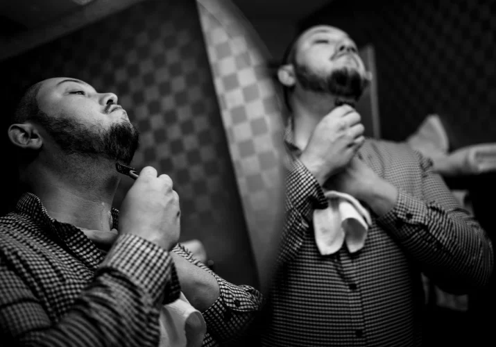 Creative Banff Wedding Photography of the groom shaving his face in a doubled mirror.