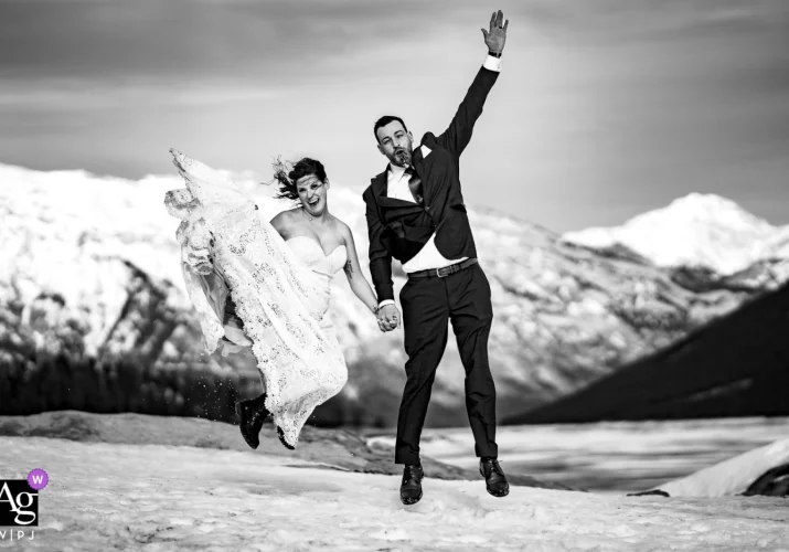 Happy bride and groom jumping after their elopement at Minnewanka Lake