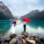 Engaged couple stand at the rocks away from each other trying to reach each other. Engagement at Lake Louise with 4Eyes Photography.